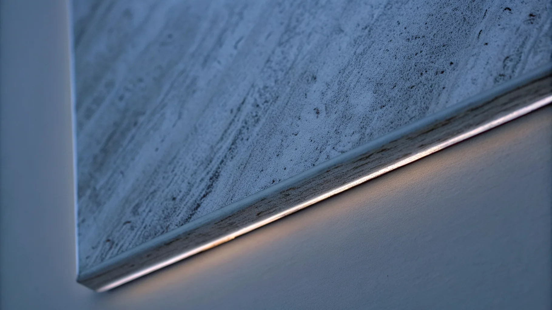 Macro study of the matt mineral composite face meeting a bead blasted aluminium edge